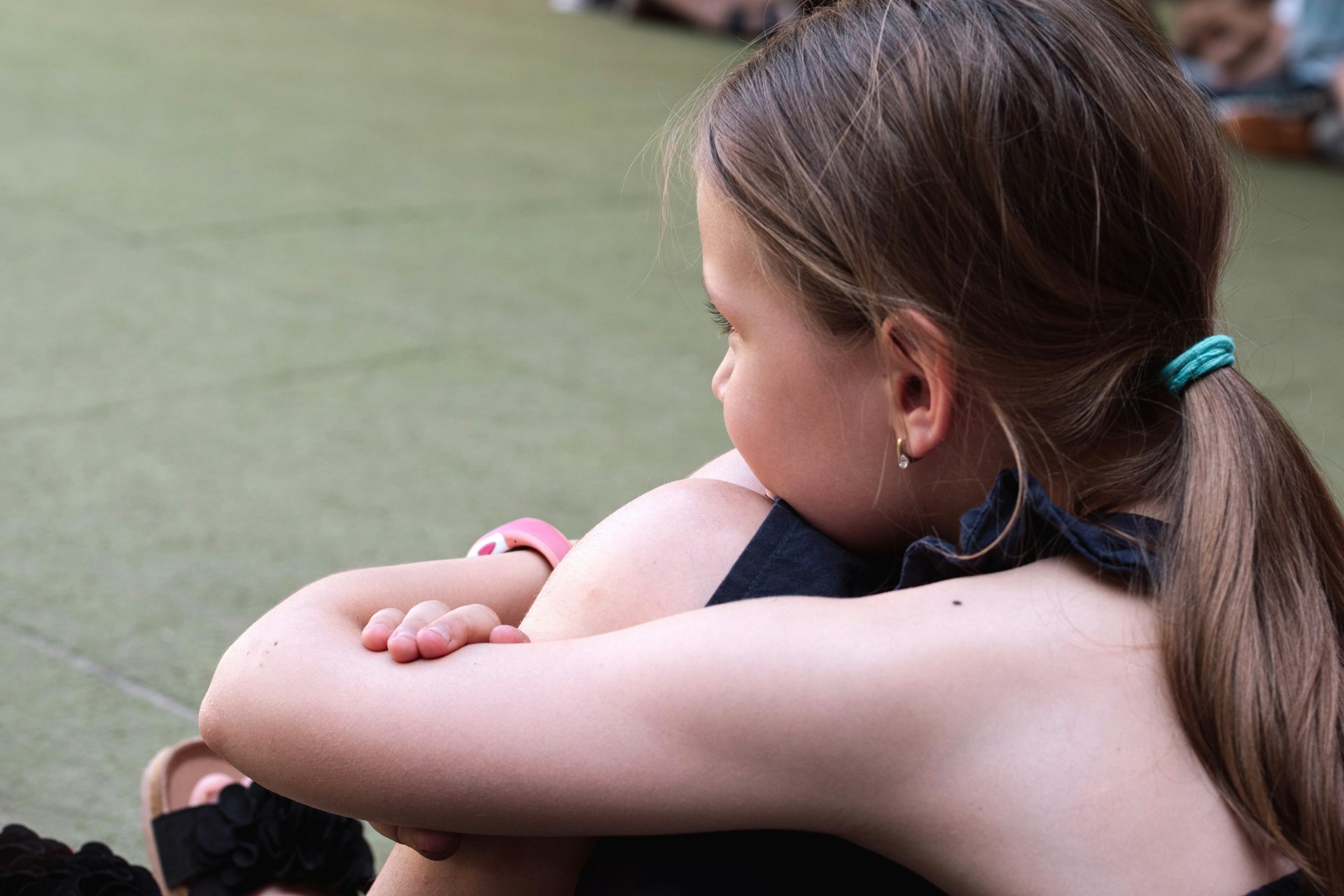 a little girl sitting on the ground with her arms crossed